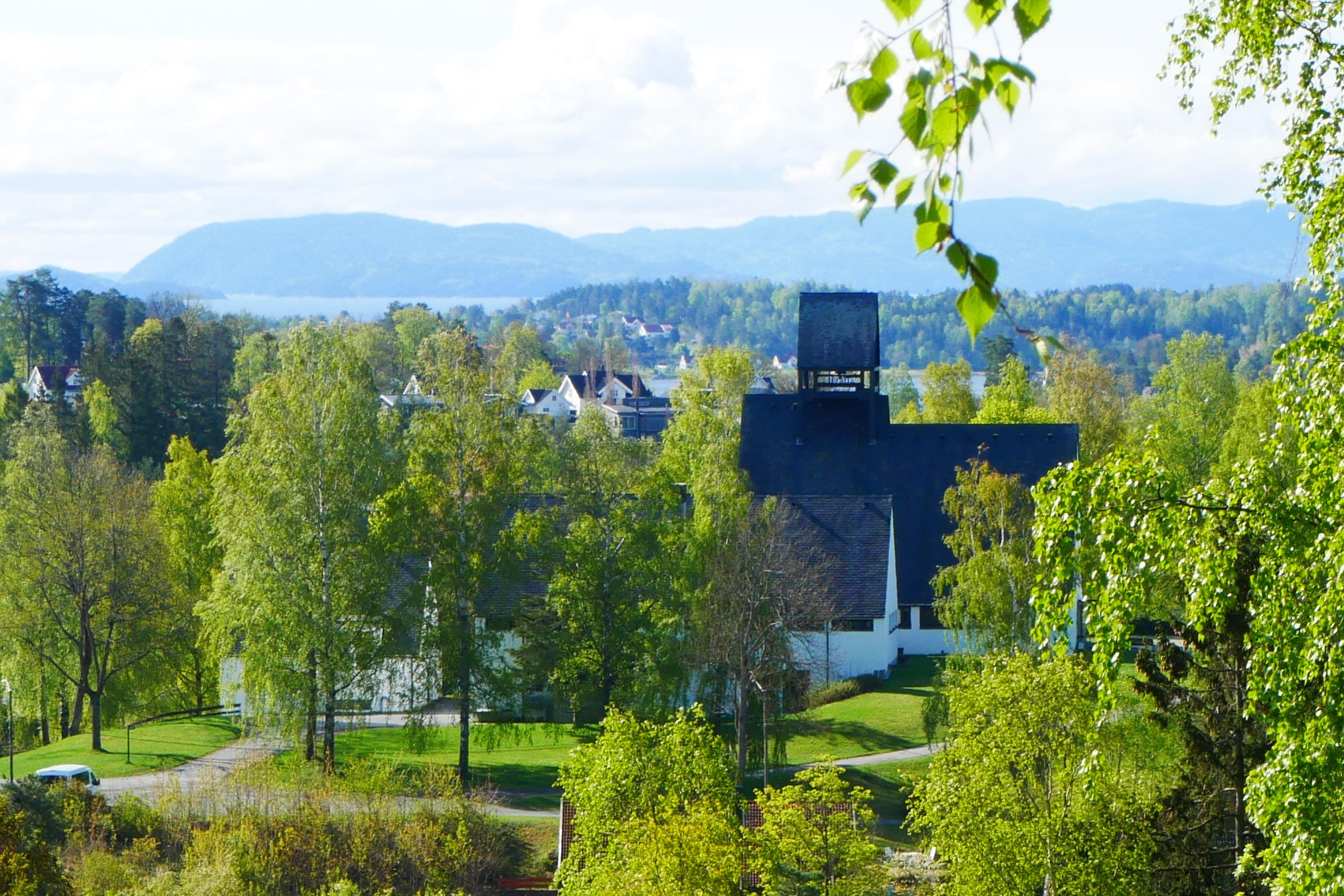Holmen kirke i frodig sommerlandskap. Fotograf: Norunn Edvardsen