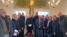 Foran Simonetta Saengers «Livets tre» i Holmsbu kapell: Fra venstre lokal kulturformidler Frank Tangen, Rådgiver kulturliv Asker kommune Gro Jerpåsen, leder av kirkens venneforening Eva Myhrene, fellesrådets rådgiver kirkebygg Reidar Haugo, venneforeningens kasserer Bjørn Bakken, prosjektleder Linda Lyngstad Marthinsen, daglig leder Asker kulturråd Erik de Mora, fylkesordfører Roger Ryberg, menighetsrådets utstillingsansvarlig Tiril Bjørkvold, avdelingssjef Jon Endre Røed Olsen, avdelingsleder Hilde Nygaard i Asker kommunes kulturavdeling, Kunstfaglig rådgiver i Asker kommune Vibeke Hermanrud, turistsjef i Asker Ann Kristin Hagby og kirkesjef John Grimsby. Foto: Hege M. Andersen/Søndre Hurum menighetsråd.