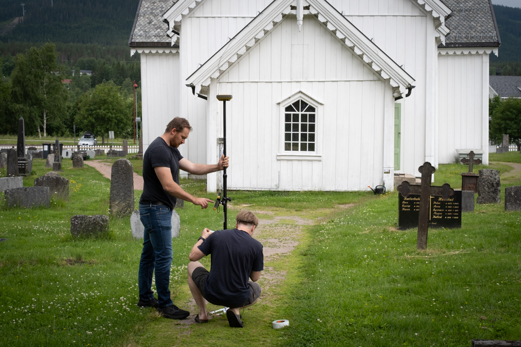 André Lianger hos Byggeplan AS og Iver Grytting fra Skiplum AS måler opp referansepunkter rundt kirkebygget. Foto: Anders Nyhuus
