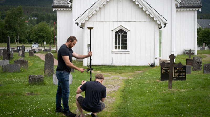 André Lianger hos Byggeplan AS og Iver Grytting fra Skiplum AS måler opp referansepunkter rundt kirkebygget. Foto: Anders Nyhuus