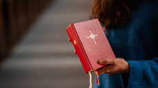 Kirkevert deler ut salmebok før gudstjeneste. Foto: Kirkerådet