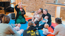 Kateketen Bente synger, forteller, blåser såpebobler og spiller av musikk fra en liten bærbar høyttaler. Foto: Den norske kirke