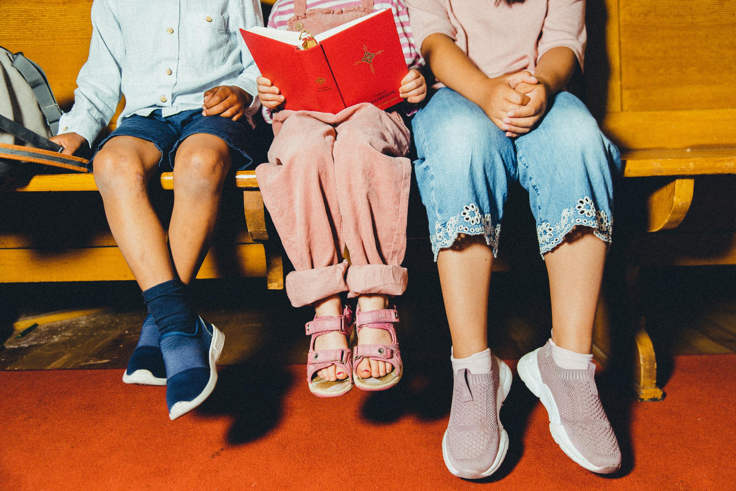 Foto Den norske kirke / Jonathan Vivaas Kise. Bilde av barn i kirka som leser salmebok sammen.