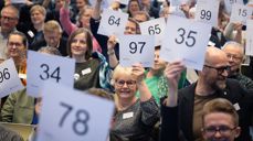 Selv om det all votering på Kirkemøtet nå foregår digitalt, stiller alltid medlemmene opp på et bilde som viser manuell votering. Foto: Den norske kirke