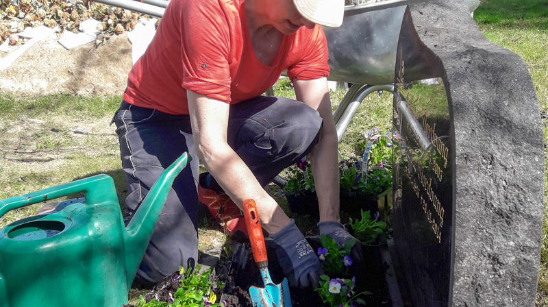 Planting av blomster ved gravminne. Foto: Mona Odden
