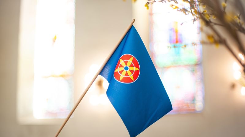 Motivet på det kvenske flagget er en solblomst, en «aurinkonkukka». Denne blomsten er funnet på eldre gjenstander i kvenske områder, benyttes stadig i kvensk kunsthåndverk. Foto: Den norske kirke.