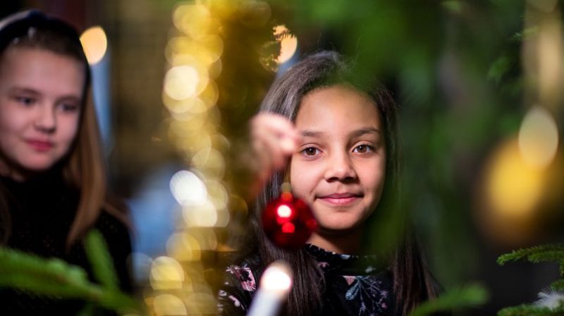 To jenter står ved et juletre.