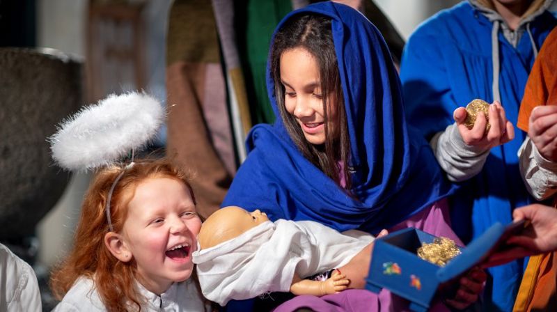 Levende julekrybbe spilt av barn. Maria holder Jesus, og en engel sitter re