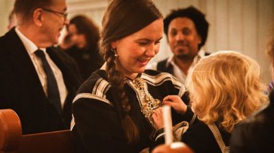 En samisk mor sitter med sitt barn på fanget i julegudstjeneste i kirken.