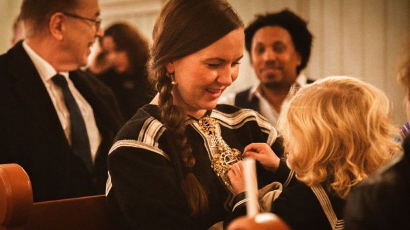 En samisk mor sitter med sitt barn på fanget i julegudstjeneste i kirken.