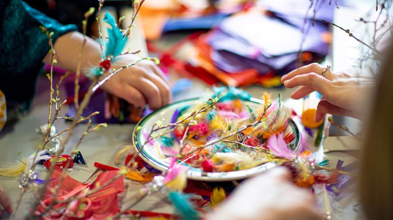 Det er karnevalgudstjeneste på fastelavnssøndag i kirken! Store og små hender pynter kvister med fargerike fjær.