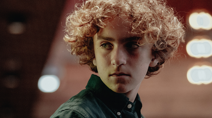 En ung mann ser tankefullt ut i kirkerommet.