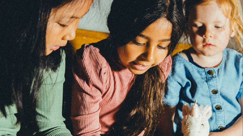 Tre barn sitter tett og konsentret