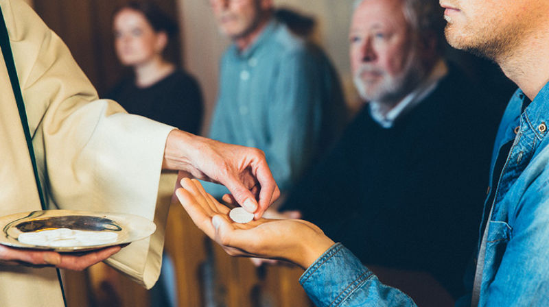 En person mottar en nattverdsoblat i hånden.