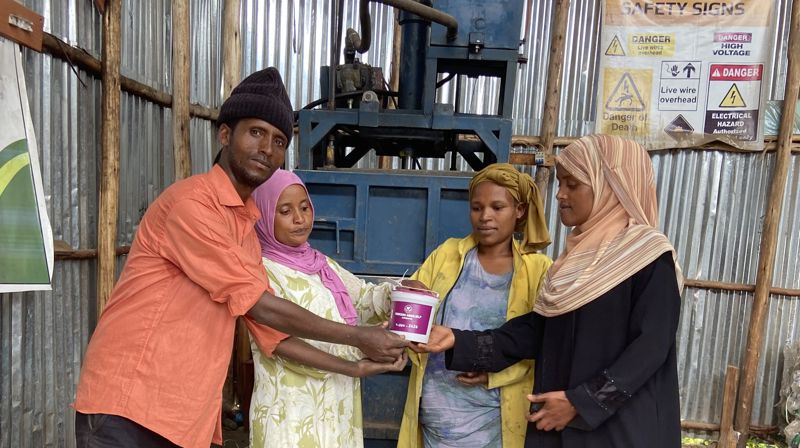 PRESSE: Her står Jemilla Senbete (nr 2 f.v.) med venner foran pressen som de har fått støtte av Kirkens Nødhjelp til å skaffe. De presser plastflaskene sammen, som siden blir remser det flettes kurver av.