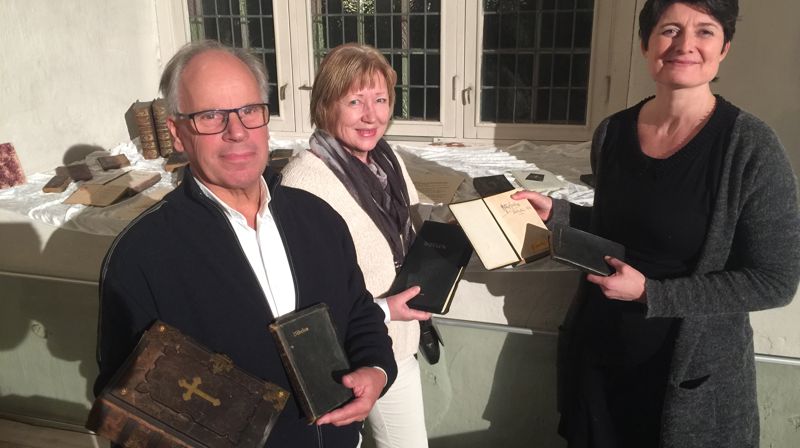 Det ble lånt inn bibler og salmebøker til utstillingen. Her viser Stein Westgaard og Jenny Åsbakk fram gamle bibler i familienes eie. Sokneprest Irmelin Grimstad Bonden til høyre på bildet. Foto: Berit Kristin Klevmoen