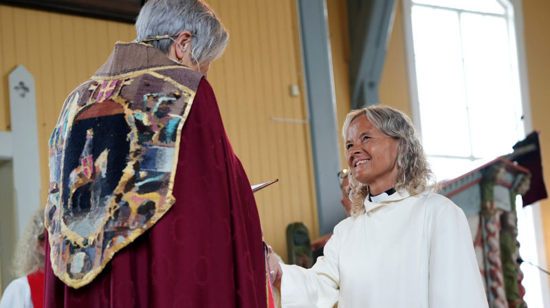 Helga Mathea Nøst mottar håndttrykket fra biskop Herborg Finnset i sin hjemkirke på Ytterøy. (Foto: Oddny Furunes Gumaer)