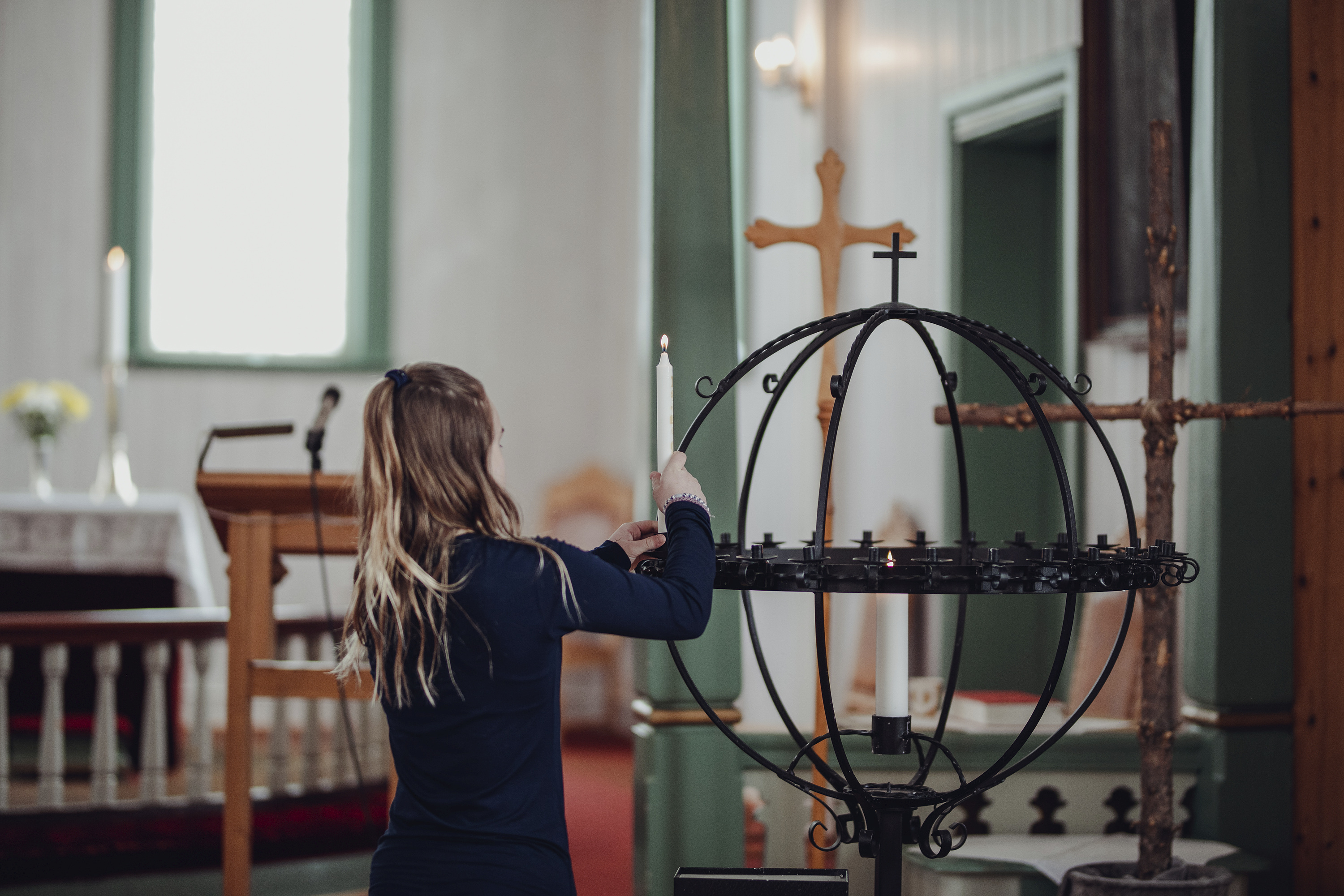 Jente plasserer et tent lys i lysgloben i Saltdal kirke. Foto: Frida Bringslimark