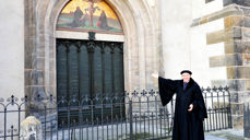 Martin Luther (Kirchenmeister Bernhard Naumann) foran døren til Slottskirken i Wittenberg. Foto: kathpress.at