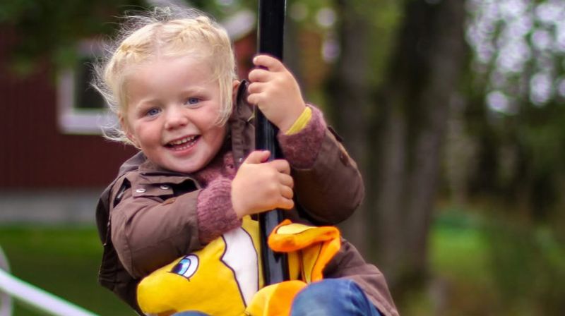 Blid jente i farta på huske.