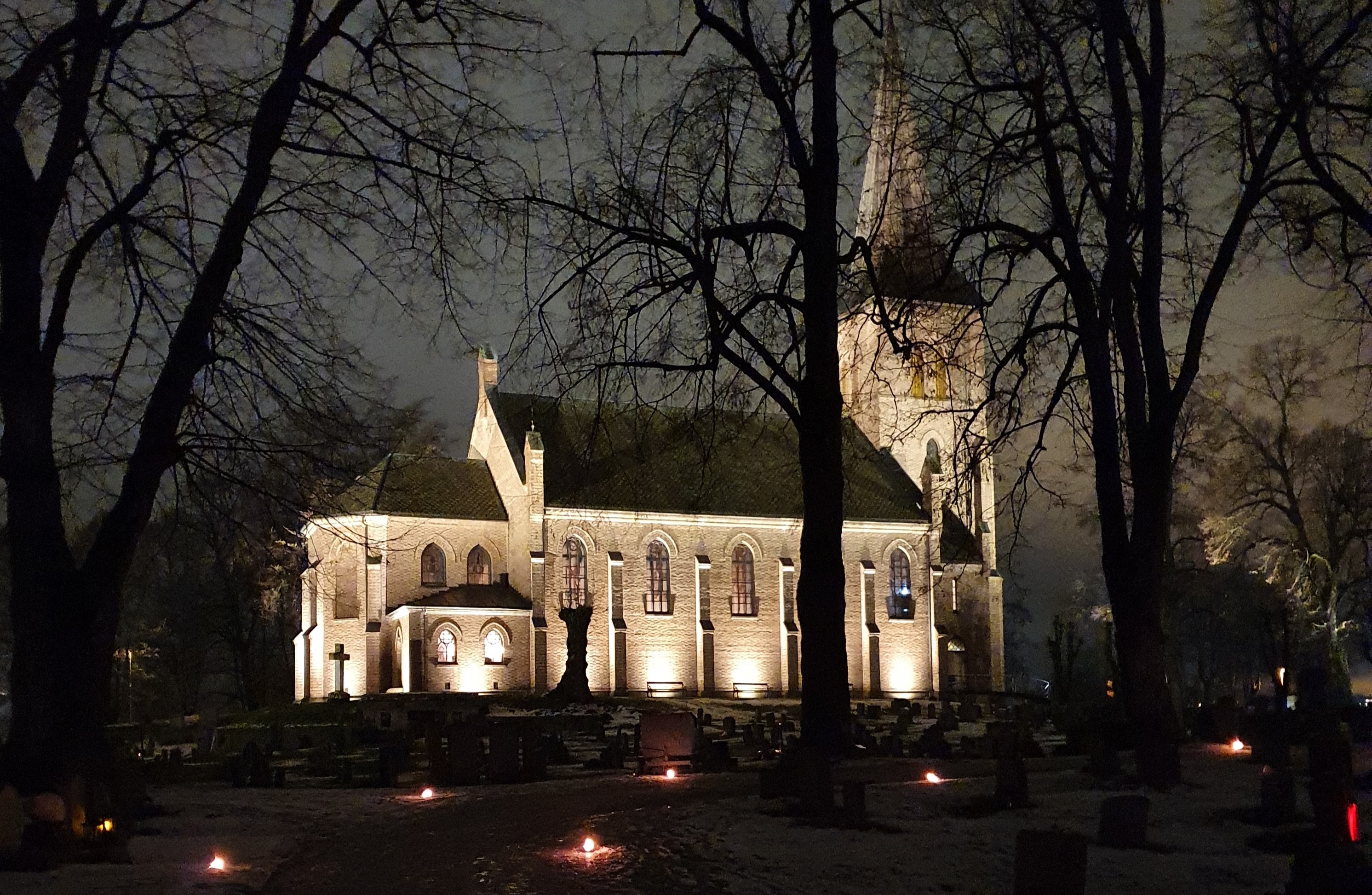 Asker kirke i flomlys med lys på gravene