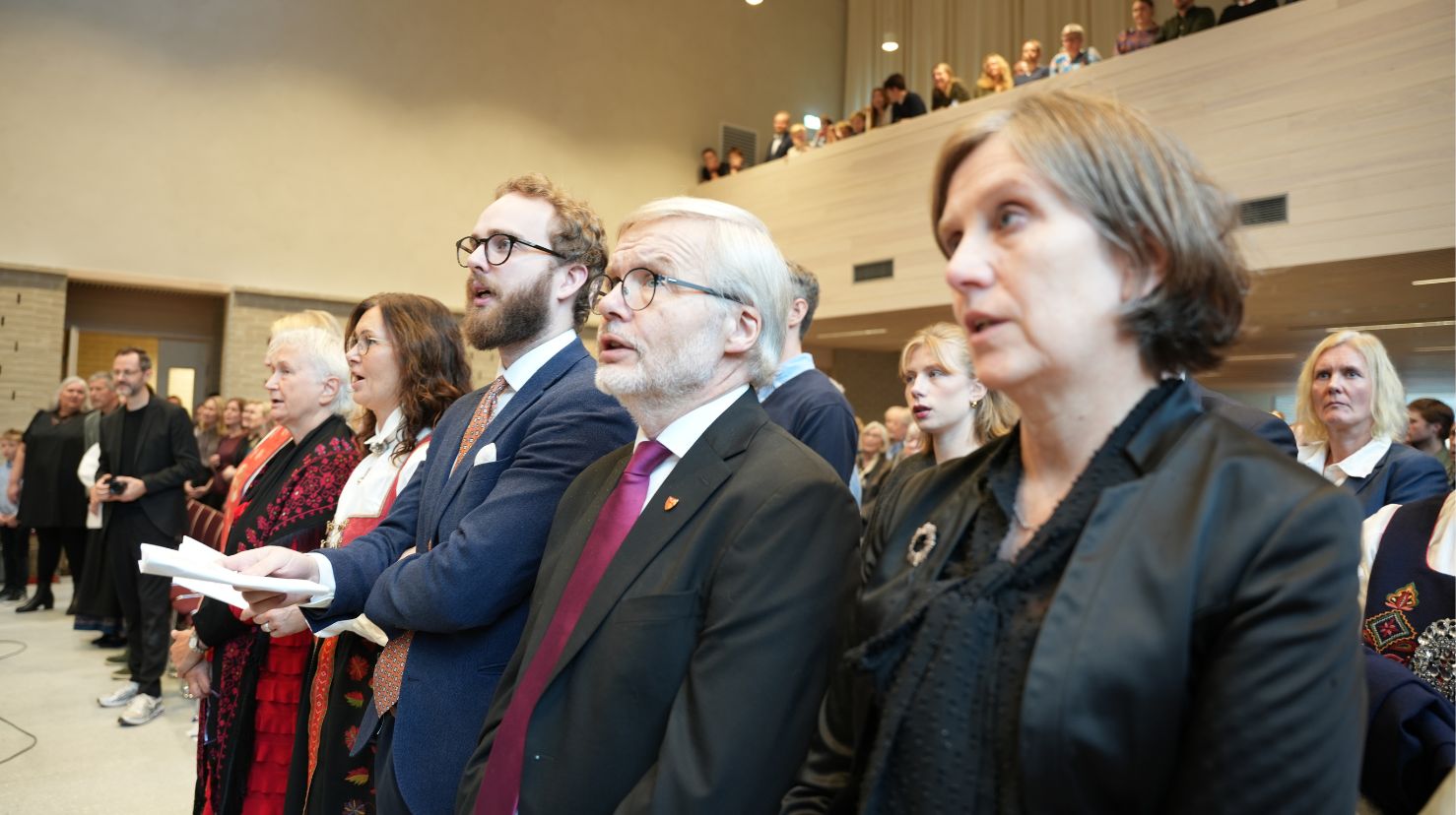 Folk i bunad og dress på første kirkerad. Foto.