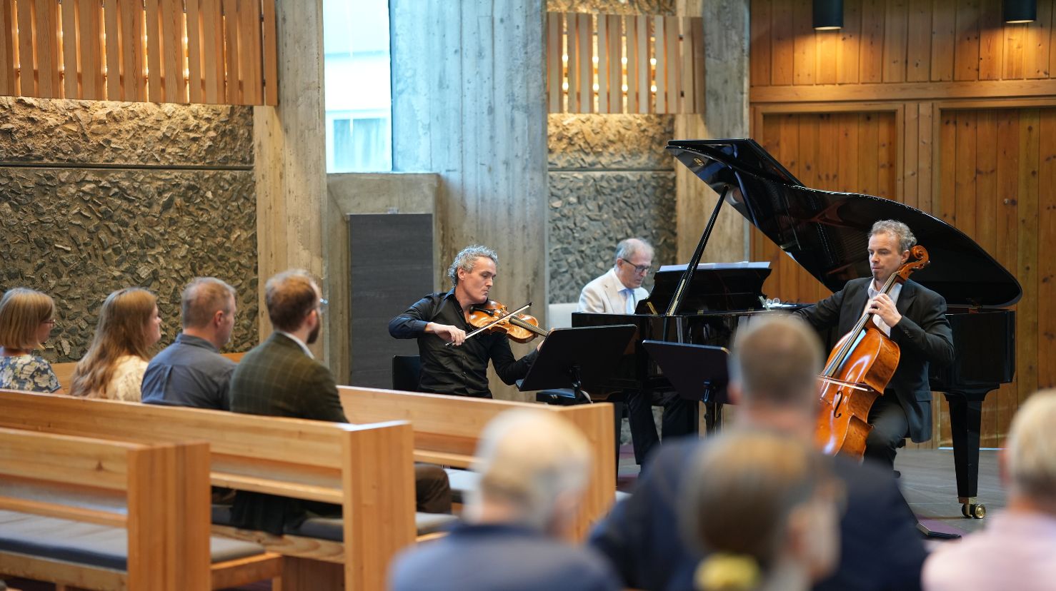 Fiolonist, cellist og pianist spiller i et kapell. Foto