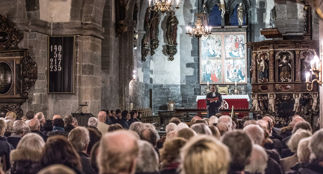 Bilde av menigheten ved gudstjeneste i Mariakirken. Sett fra bak i kirkerommet.