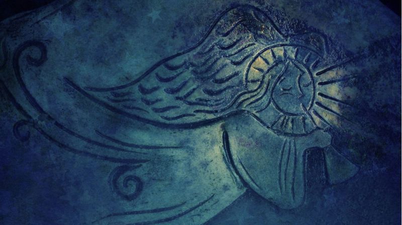 Relieff mot mørkeblå bakgrunn av engel som bles i trompet