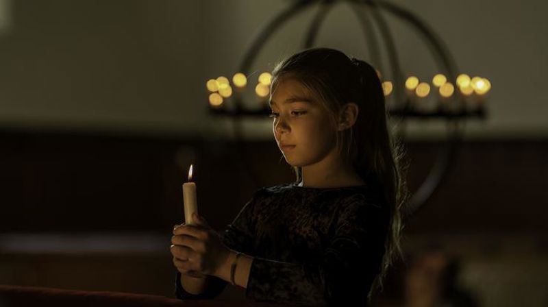 Allehelgen: jente som holder et lys i hendene, med lysglobe i bakgrunnen. Foto: Jarle Hvidsten