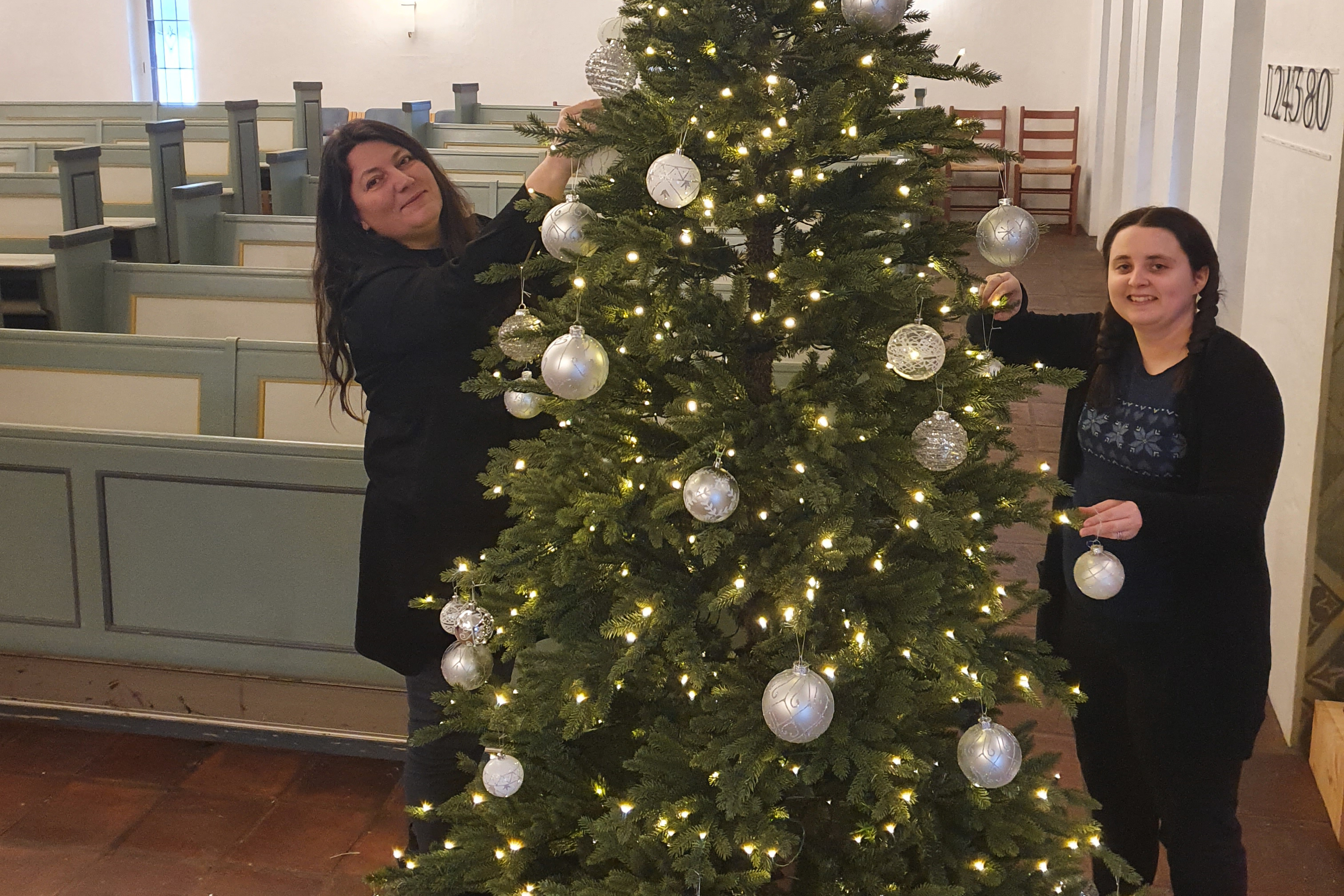 Elin Wood og Beate Koldal pynter juletreet i Bakkebø kirke.