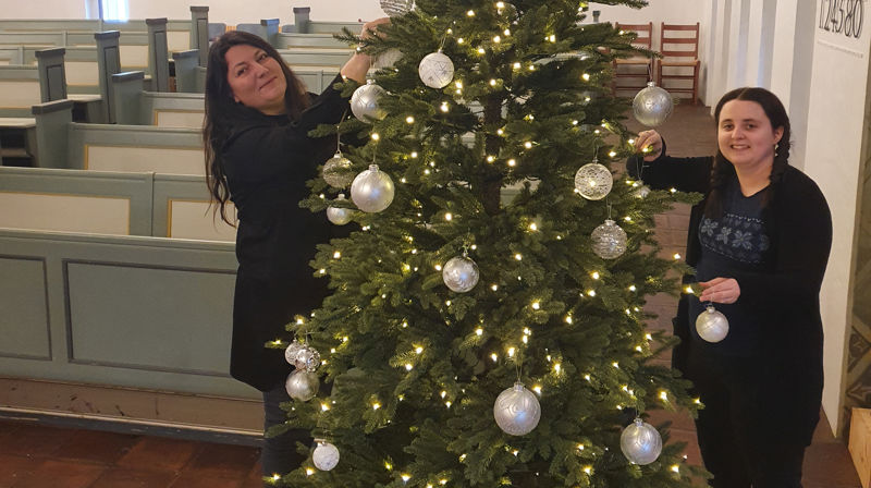 Elin Wood og Beate Koldal pynter juletreet i Bakkebø kirke.