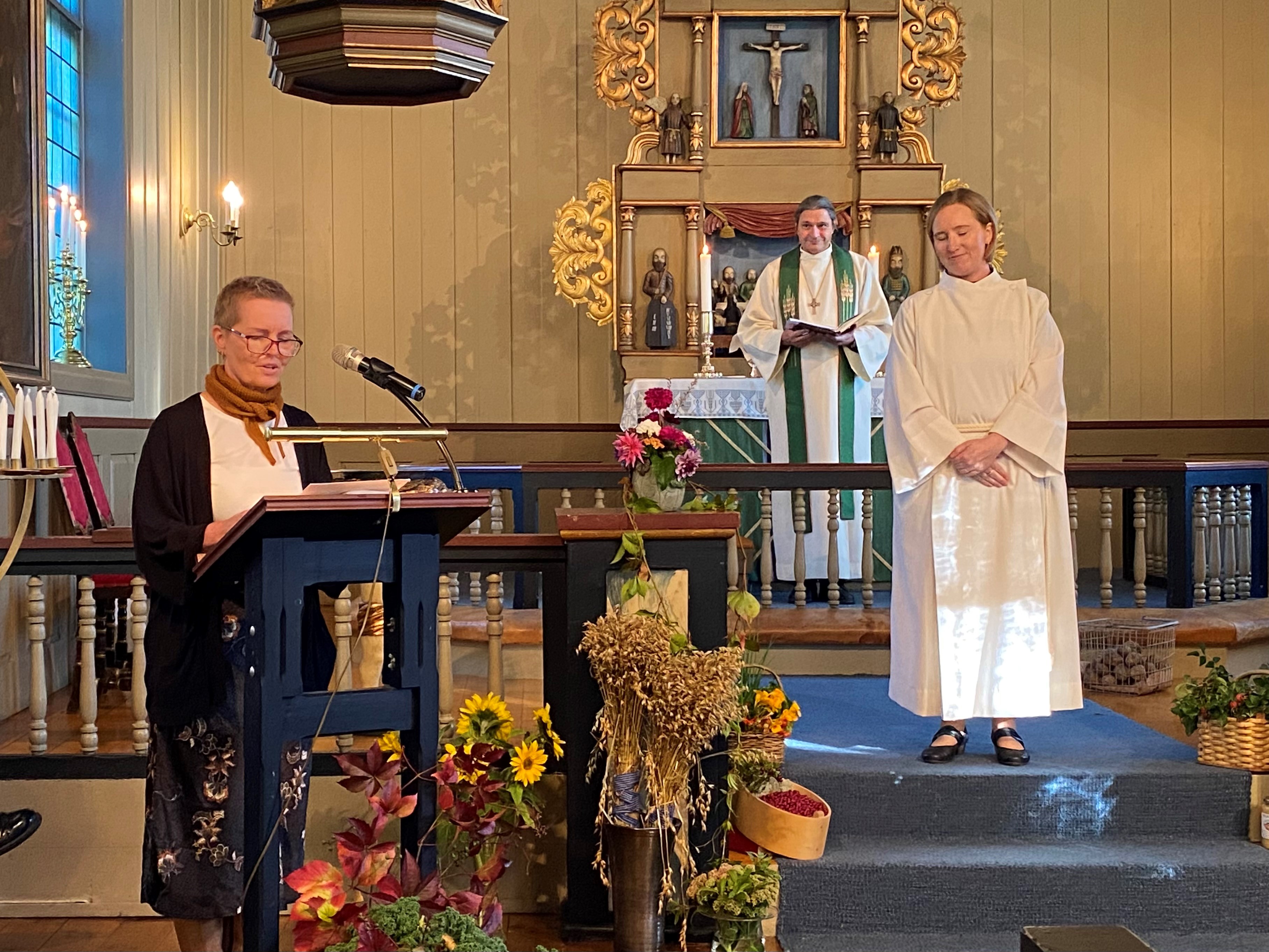 Eli-Kristin hadde innsettelsesgudstjeneste til prestetjeneste i Nes kirke i september 2023. Tone Reidem, menighetsrådslederen i Brandbu sokn, ved lesepulten, prost Tor Even Fougner og Eli-Kristin (foto Inger Stensrud Haug).