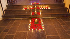 Tirsdag 29. juli på Olavsdagen/Olsok ønsker vi velkommen til tradisjonsrik olsokmesse i Mariakirken kl. 20.00. Her er bilde av kors formet av lys og roseblader ved en tidligere olsokmesse samme sted (foto: Anne-Lise Mellum).