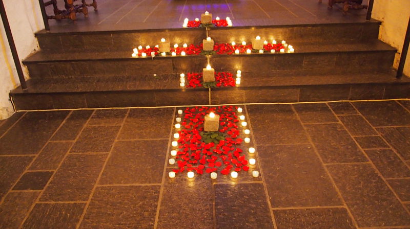 Tirsdag 29. juli på Olavsdagen/Olsok ønsker vi velkommen til tradisjonsrik olsokmesse i Mariakirken kl. 20.00. Her er bilde av kors formet av lys og roseblader ved en tidligere olsokmesse samme sted (foto: Anne-Lise Mellum).