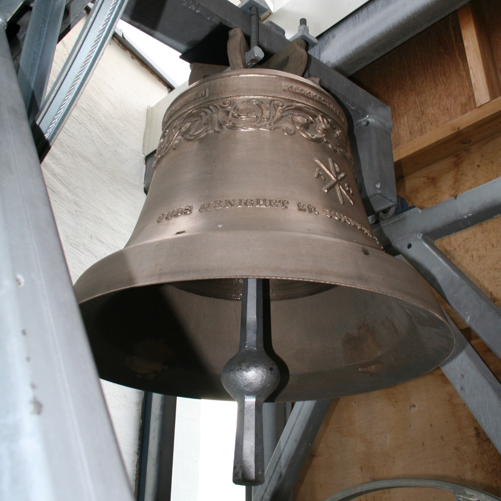 Den ene av de to kirkeklokkene som henger i klokketårnet ved Grymyr kirke. Foto: Kirken i Gran. 