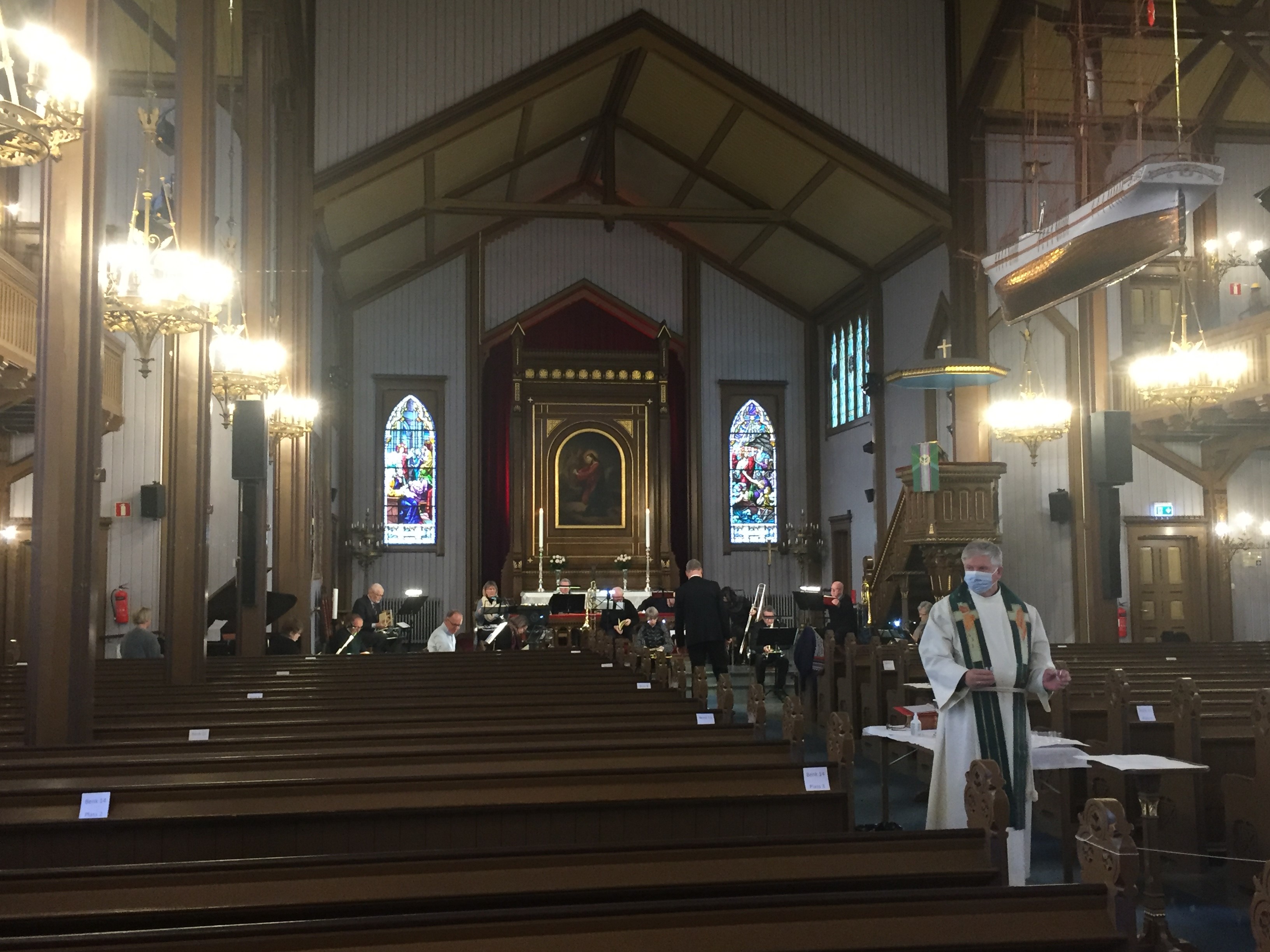 Sogneprest Hjalmar Bjerga forrettet nattverd under kirkevandringen. I bakgrunnen messingblåsegruppe som gjestet menigheten denne søndagen.