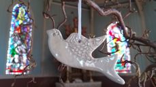 Medan barnet vert døypt, vert eit dåpslys tent og ei kvit dåpsdue blir hengt opp i greina for å symbolisere dåpen.