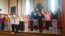 Barn står i kortrappa og strekker hendene i været.