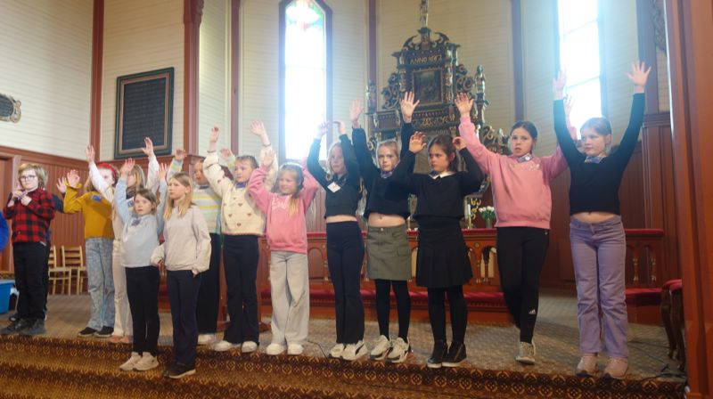Barn står i kortrappa og strekker hendene i været.
