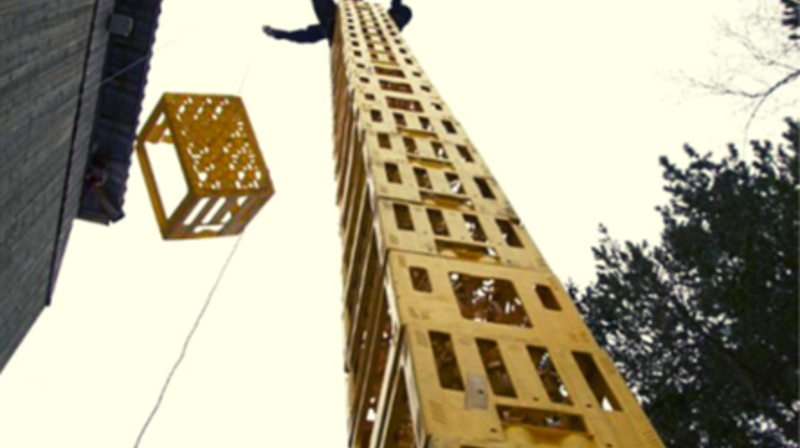 Bilde av en høy stabel med bruskasser, og en person på toppen av bruskassene.