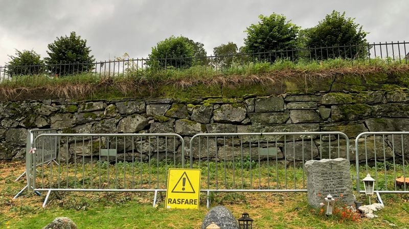 Støttemur med sikringshekk og skilt Rasfare.