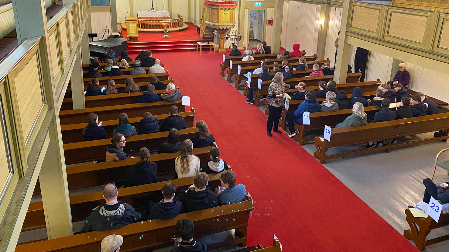 Konfirmantar og foreldre sitt klare i Fjell kyrkje for å gå med bøsser til fasteakjonen