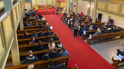 Konfirmantar og foreldre sitt klare i Fjell kyrkje for å gå med bøsser til fasteakjonen