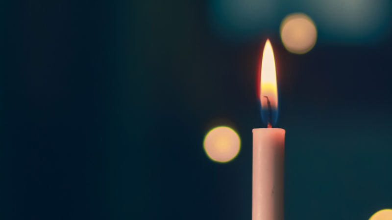 Et hvitt steartinlys står og brenner med difus mørkeblå bakgrunn