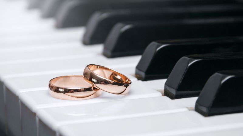 To gullringer ligger på tangenter på et piano