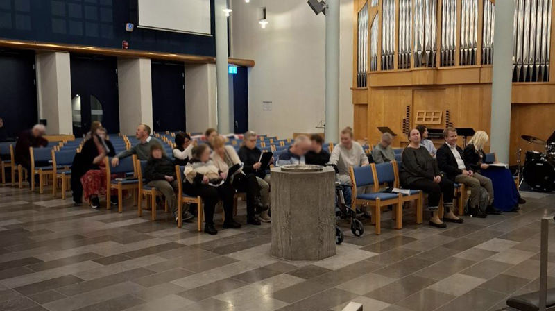 Mennesker sitter i stolradene i kirken