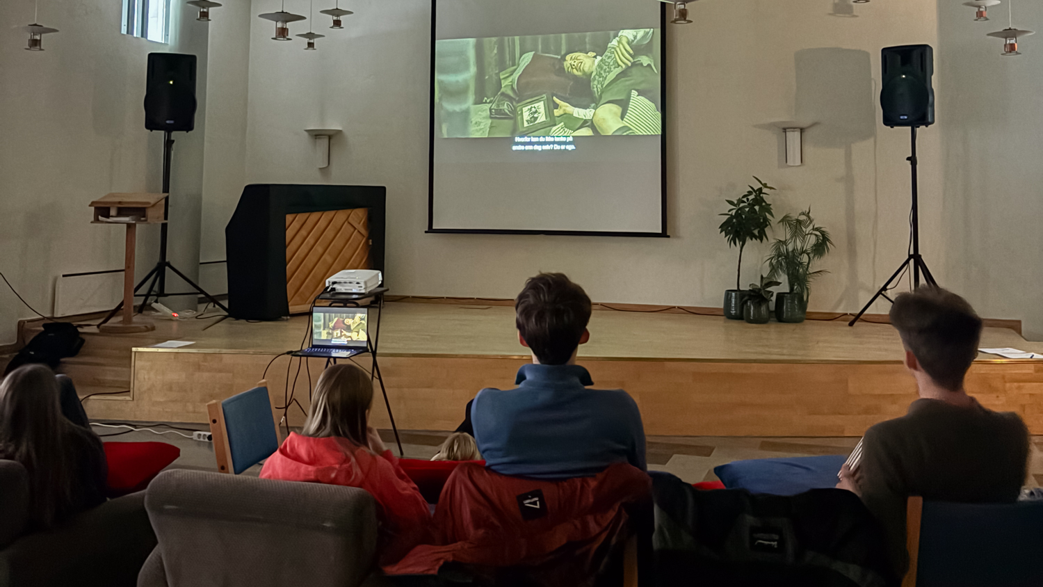 Ungdommer sett bakfra ser p&aring; film p&aring; et lerret