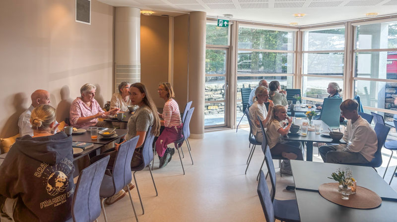 Mennesker sitter langs og ved bord og prater og spiser