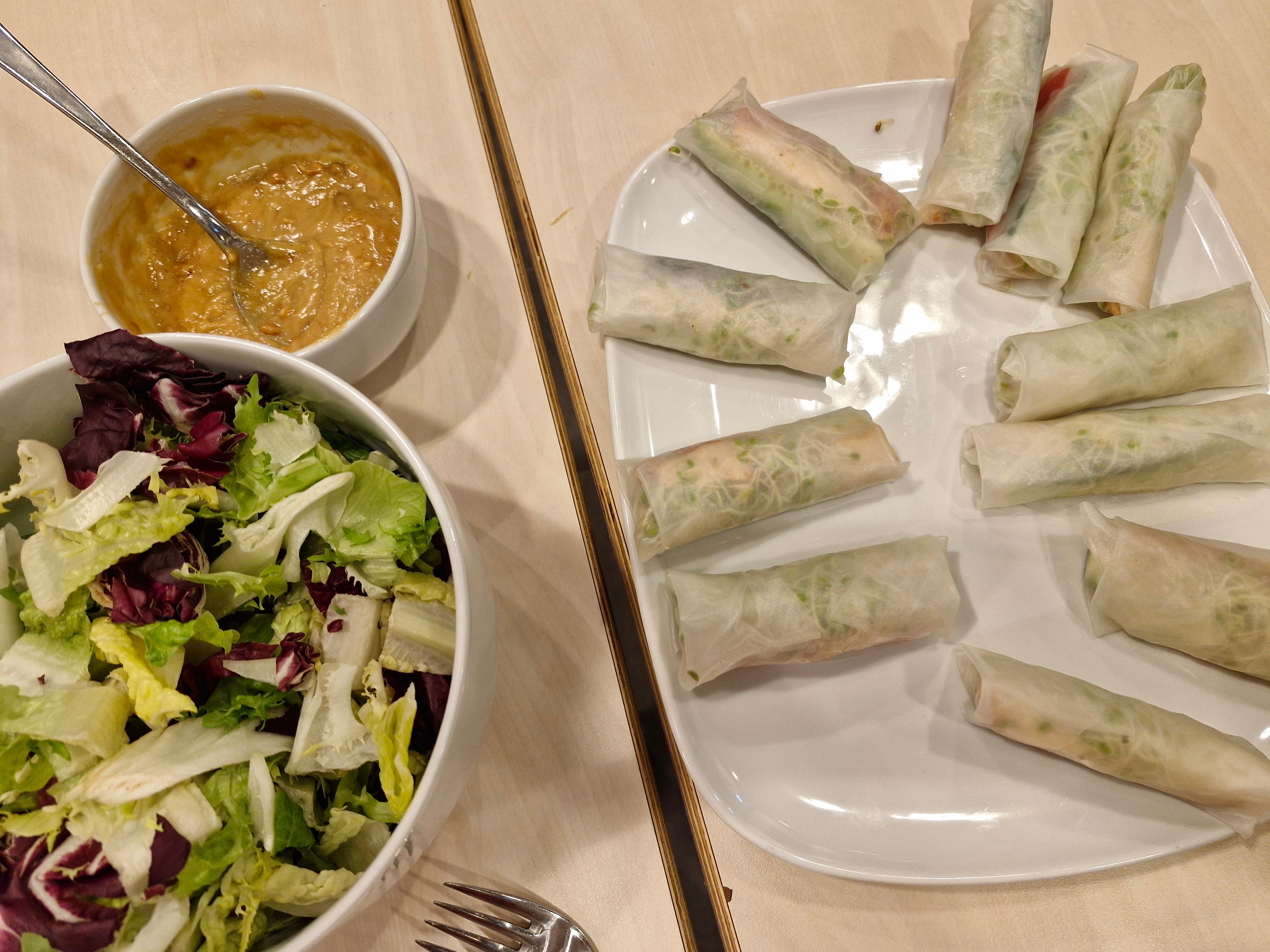 Til høyre er eit fat med vårruller og til venstre ei skål med saus og si skål med salat.